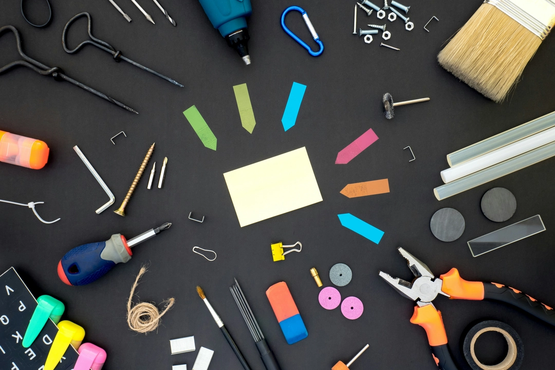 A variety of tools arranged on a black surface, including a screwdriver, drill, pliers, paintbrush, and various hardware. This image symbolizes the versatility and efficiency of the Python functools module for code optimization, showcasing how different tools can enhance coding projects.