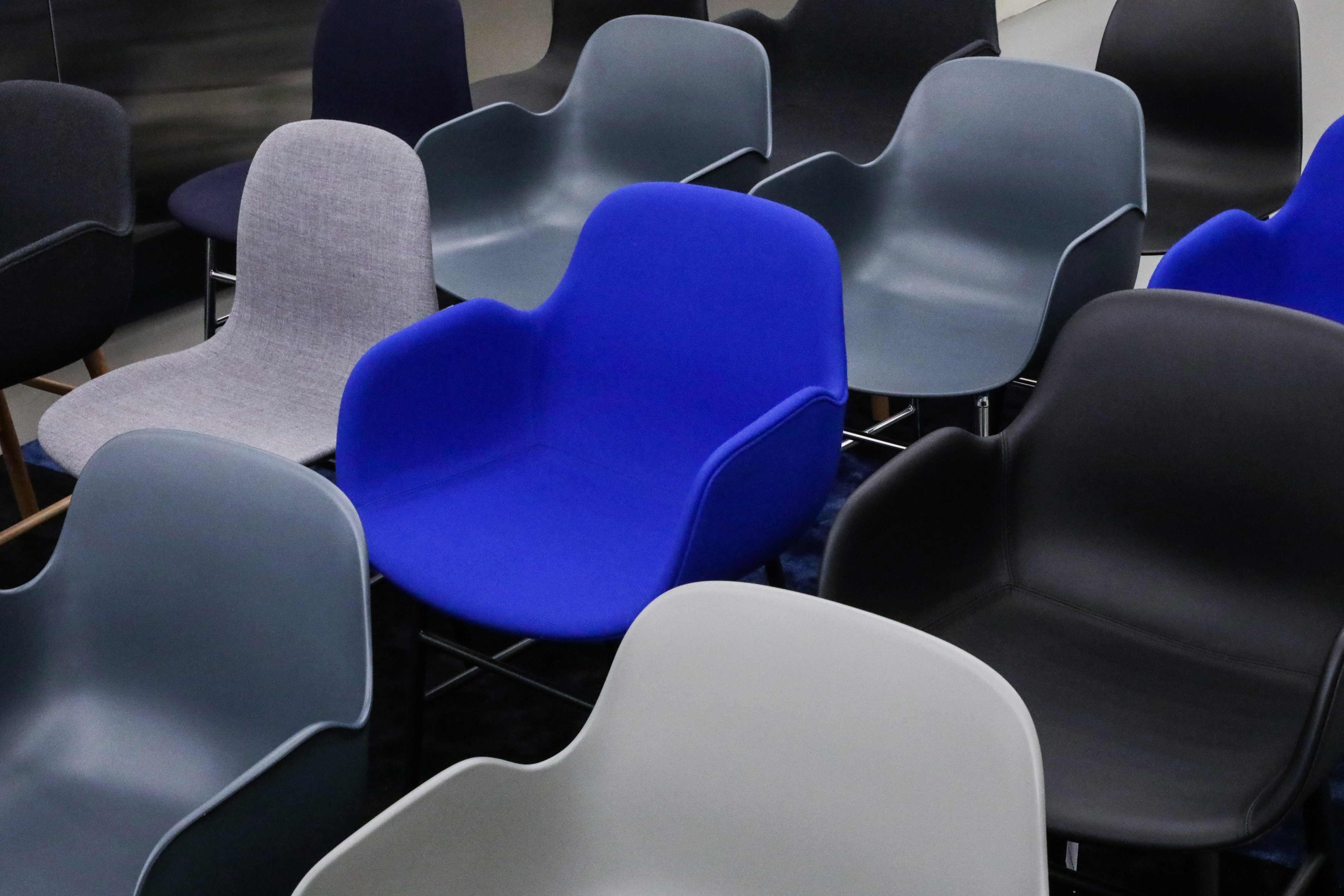 Assorted ergonomic chairs in shades of gray, blue, and black in a modern office setting, reflecting Dieter Rams' design principles in workplace furniture for enhanced comfort and style.