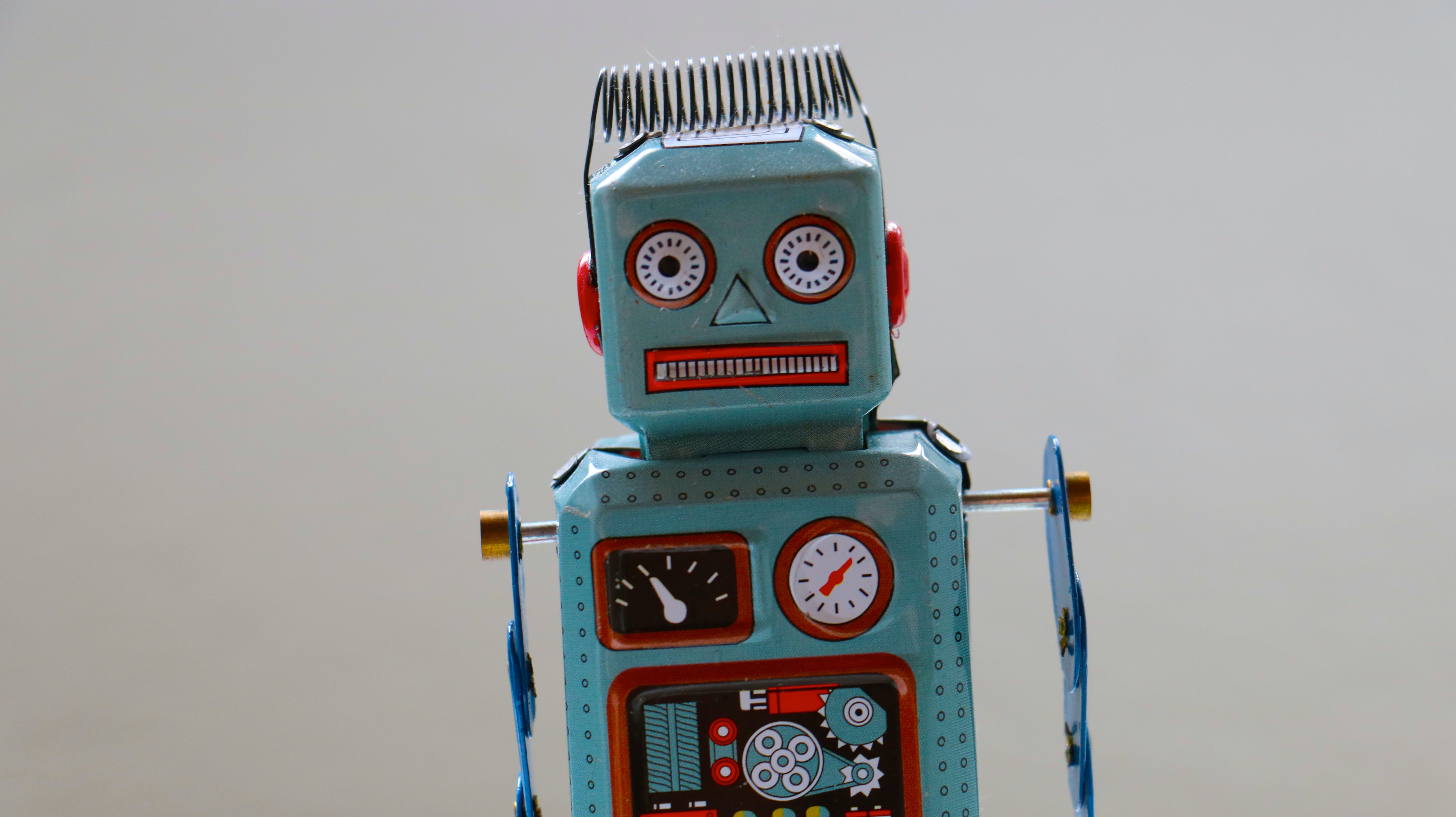 Vintage tin robot toy on a white background exemplifying functional programming principles in Python, symbolizing the automation and precision of code.