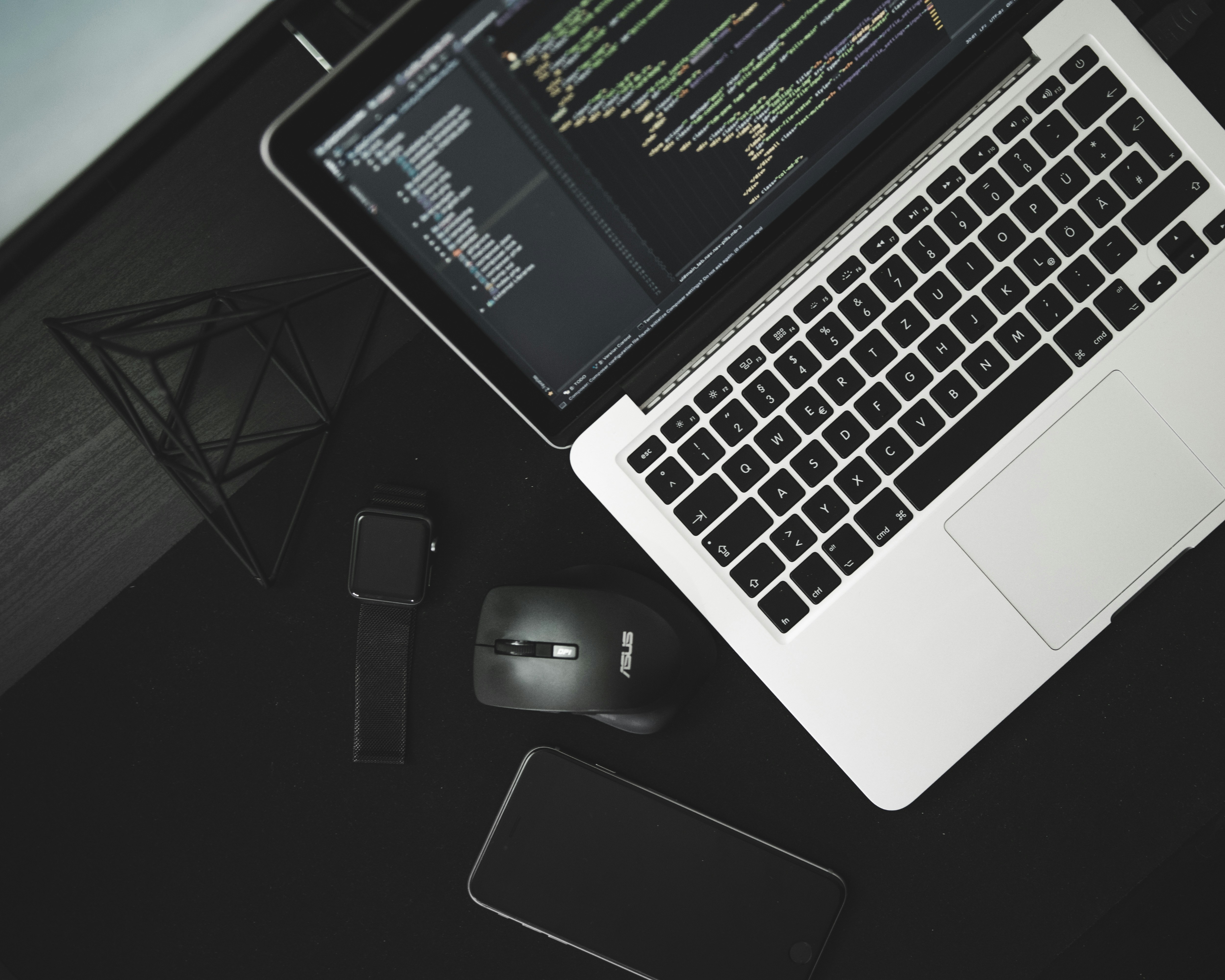 Modern workspace featuring a laptop displaying code, relevant to learning how to implement semantic versioning in software projects, alongside other tech gadgets like a smartwatch and smartphone.